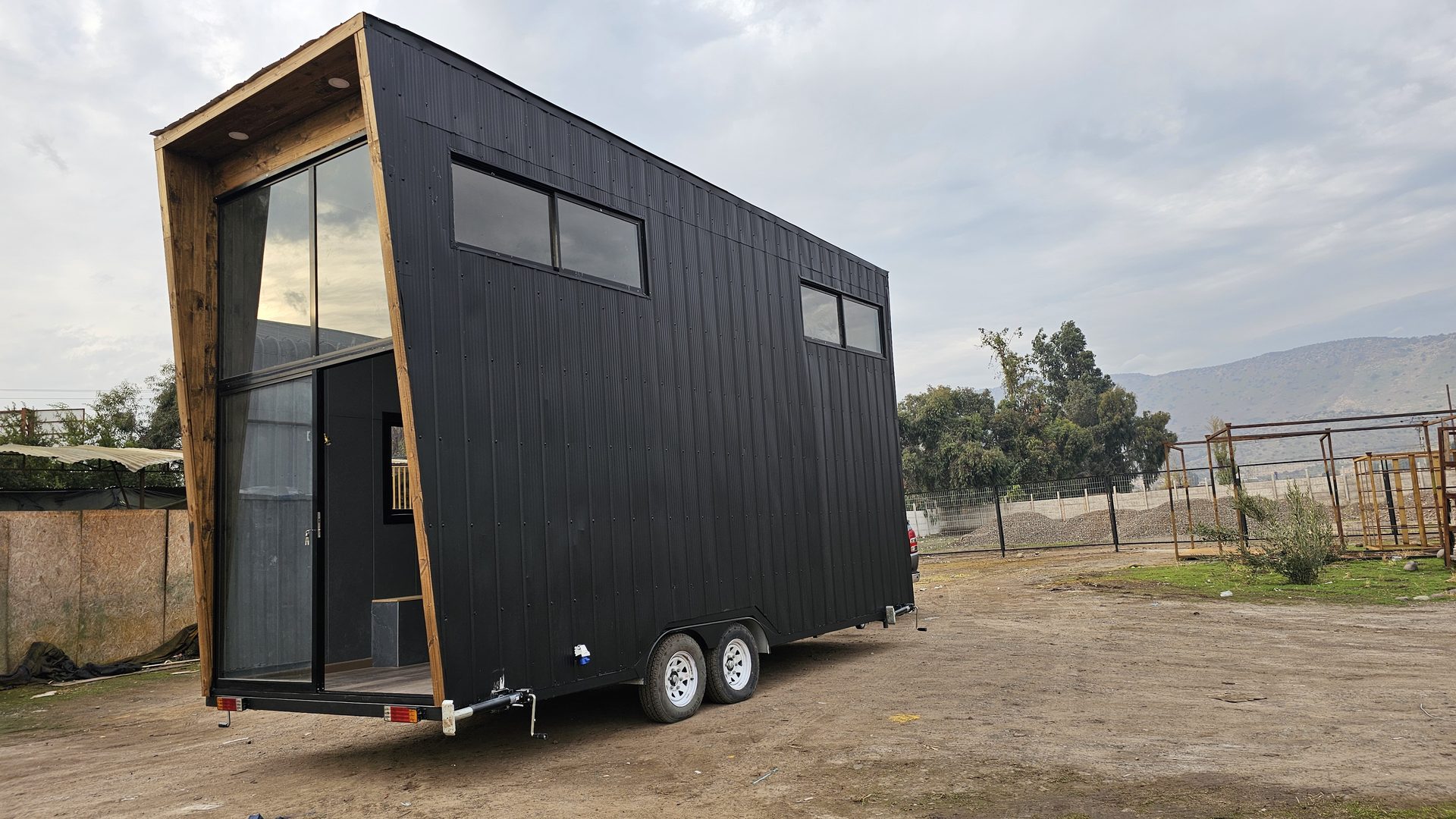 Andes Haus: tiny house de dos pisos con fachada vidriada y marco de madera, sobre ruedas